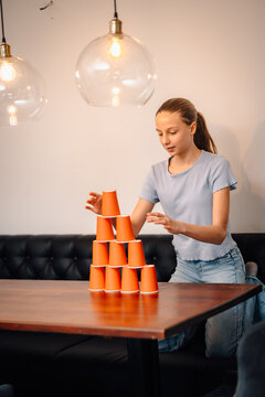 Girl stacking orange cups pyramid in concentration game