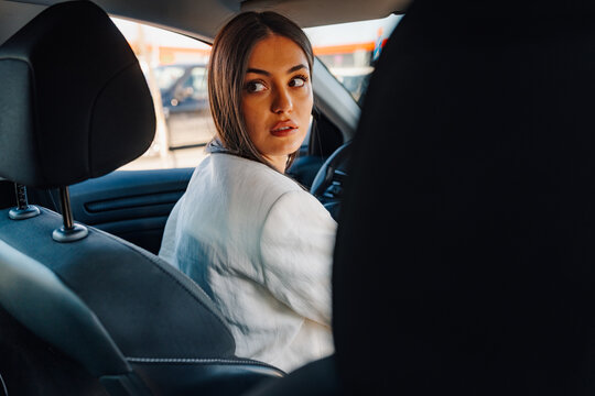 Young woman driving car looking back reversing