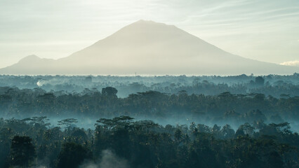 A spectacular sunrise view of Mount Agung, the highest and most iconic volcano in Bali, Indonesia. The dramatic mountain landscape, glowing morning light, and tropical scenery create a stunning travel
