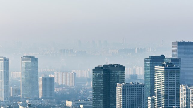 Modern city skyscrapers obscured by thick gray smog and pollution