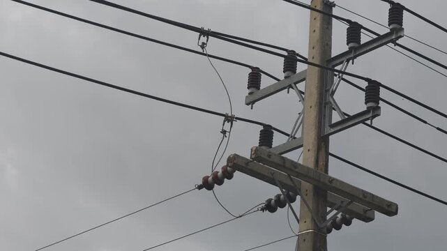 Video of a glowing electrical arc sparking at a hotline clamp connection on high voltage overhead power lines at a distribution network pole.