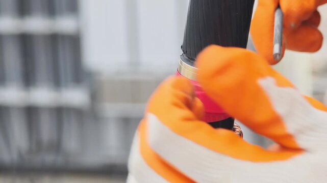 Close up video of gloved hands using a round file to smooth the semiconductor layer of a high voltage underground cable during termination preparation.