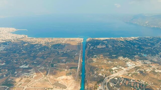 Corinth Canal, Greece. Drone footage of the narrow sea-level shipping canal cutting through the Isthmus of Corinth, with steep limestone walls and turquoise water under bright summer light. Drone foo