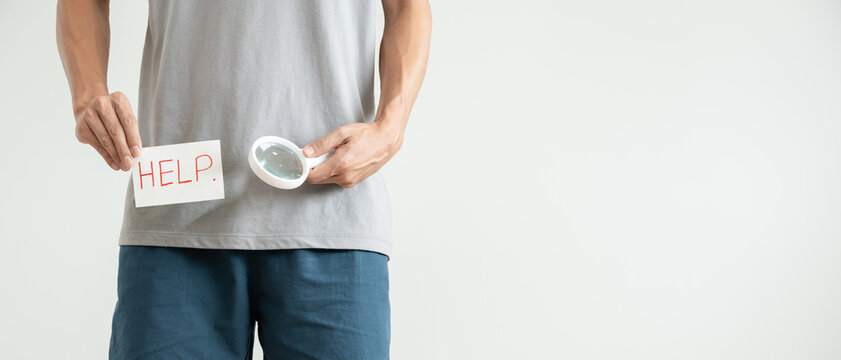 Man uses magnifying glass for size problems, discomfort from disease and inflammation. Venereal, testicular cancer. bladder problems, erectile dysfunction, premature ejaculation, prostate cancer.