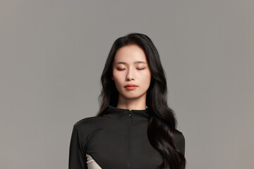 Fototapeta premium Calm young woman in black futuristic outfit with eyes closed