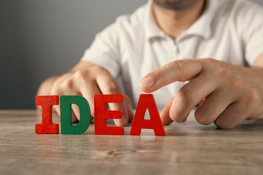 Man building word Idea with wooden letters on table, close-up