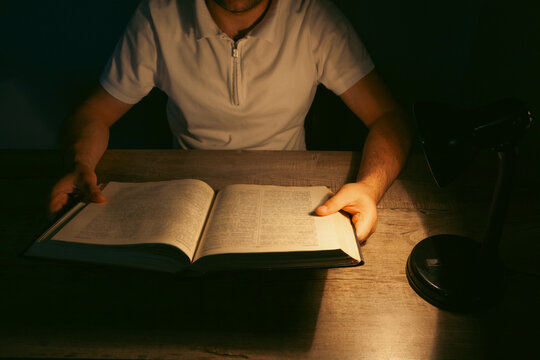 Man reading a book in the dark at night.