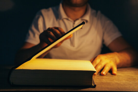 Man reading a book in the dark at night.
