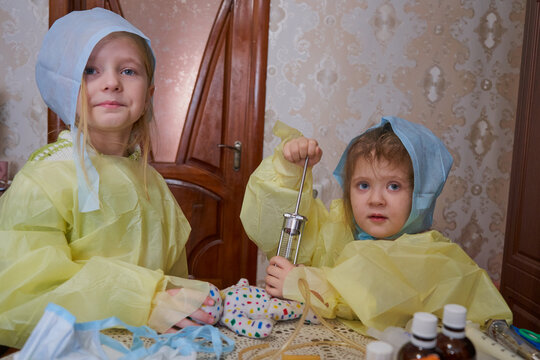 Two little children in medical gowns and caps play doctors, Children's dreams about the future profession, playing in doctor and patient