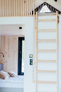 Vertical shot of wooden tiny house loft ladder, bedroom and compact sleeping area