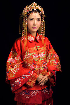 Asian Chinese girl wearing ancient costume and red makeup against a black background