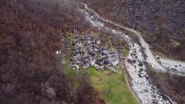Foroglio village sits beside a rocky river in Val Bavona, Switzerland, right drone orbit shot.