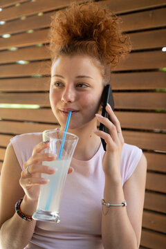 Young woman talking on a mobile phone in a cafe and smiling