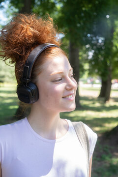 Young woman portrait listening to music on headphones in the park