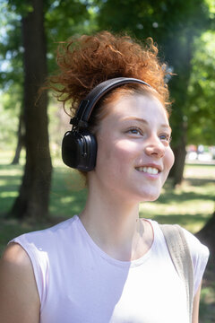 Young woman portrait listening to music on headphones in the park