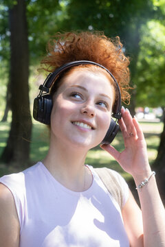 Young woman portrait listening to music on headphones in the park