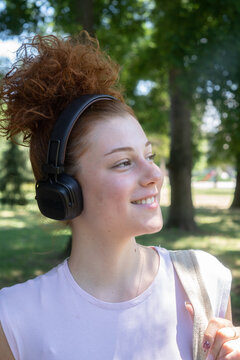 Young woman portrait listening to music on headphones in the park