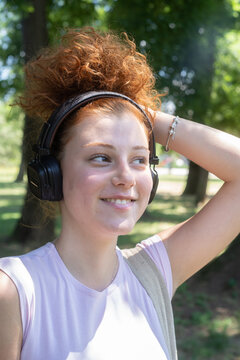 Young woman portrait listening to music on headphones in the park
