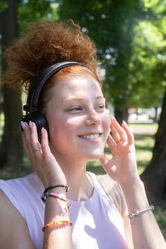 Young woman portrait listening to music on headphones in the park
