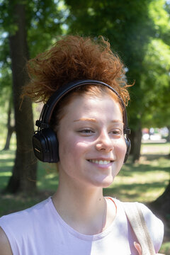 Young woman portrait listening to music on headphones in the park