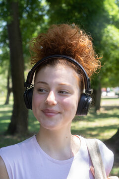 Young woman portrait listening to music on headphones in the park