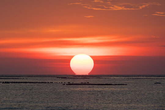 Dramatic sunset over the ocean horizon, colorful sky reflecting on the sea water.
