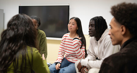 Obraz premium Diverse group of young students engaging in conversation, learning, and cooperation in a classroom setting