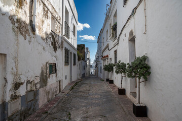 Obraz premium Narrow cobbled street in the historic centre of Tarifa, Spain, lined with whitewashed houses and traditional Andalusian architecture under a bright blue sky
