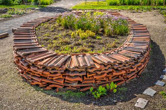 Creative garden bed border made from stacked terracotta roof tiles