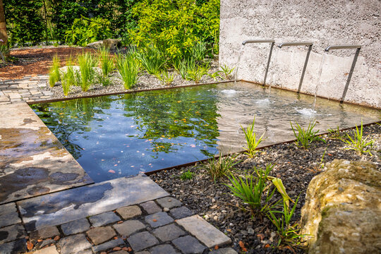 Modern garden water feature with cascading water jets and stone paving