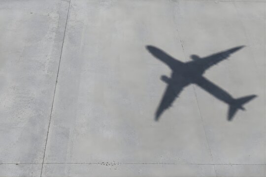 Airplane shadow flying over empty concrete pavement, minimal aviation and journey stock photo
