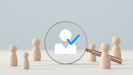 Wooden figures standing around a magnifying glass examining a selected user profile icon with a blue checkmark on a plain light background © Anonymous