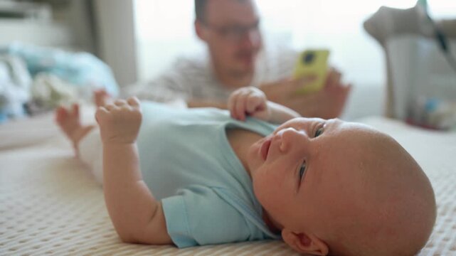 Neglected newborn baby crying on a bed while the inattentive father is distracted by his smartphone, illustrating a lack of paternal attention and the negative impact of technology addiction