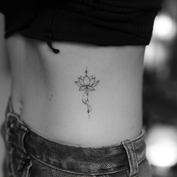 Elegant fine line lotus flower tattoo on woman side waist