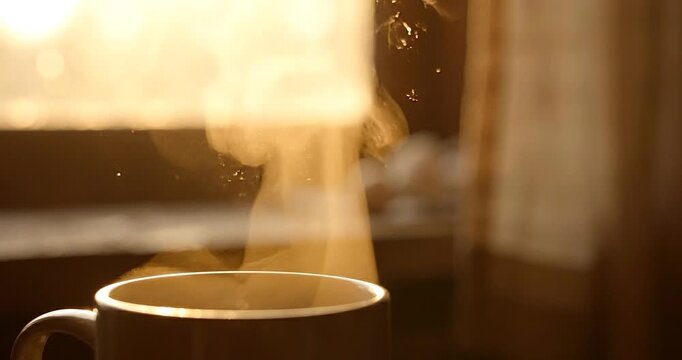 Hot coffee steaming cup with steam rising by window in morning light, warm sunlight bokeh, cozy mood beverage coffee cup close up aroma, golden sunrise breakfast indoor glow