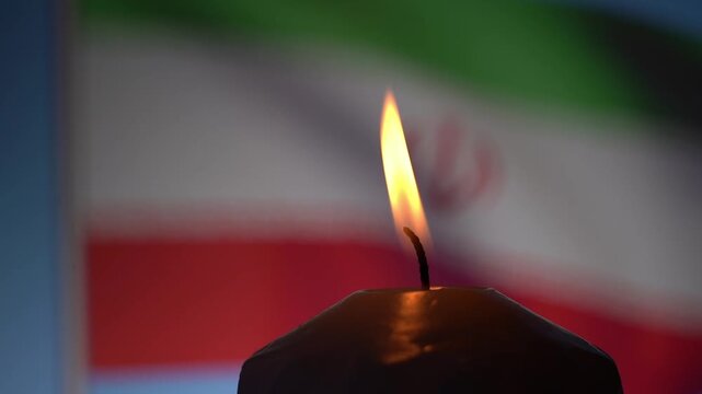 Close-up of a lit candle flame. Iranian flag softly blurred behind it. Warm light illuminates the wick. Symbol of remembrance or hope. Used for cultural or historical contexts