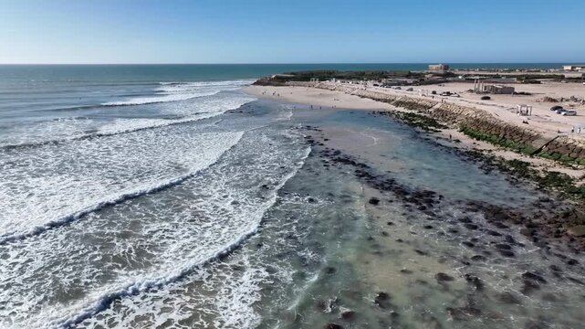 Drone aerial view of the Atlantic coastline near Dakhla, featuring rocky shores, rolling waves, and one of Morocco's world-renowned destinations for surfing and water sports.