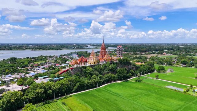 Drone wide shot of Wat Tham Suea temple and green rice paddies in Thailand