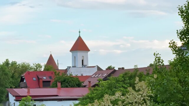 Pungert Tower and the Church of St. Sebastian, Fabian and Roch rise above red rooftops and green trees in Kranj old town, Slovenia.