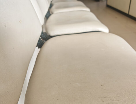 texture view of empty white vinyl chairs in a terminal station or clinic waiting area, showing detailed surface material.