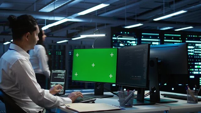 Engineer uses a replaceable screen device in a server farm with a chroma key computer monitor, supporting screen replacement, device mockup and energy efficiency during secure technical operations
