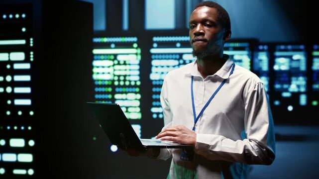 African American engineer verifies redundancy for server systems in a data center, supporting automatic failover, rapid reconfiguration and dependable cluster continuity.