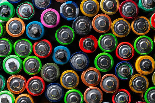 Colorful used alkaline batteries background pattern. Top view of many assorted colorful alkaline batteries, closeup. Great for recycling, environmental conservation and renewable energy concepts