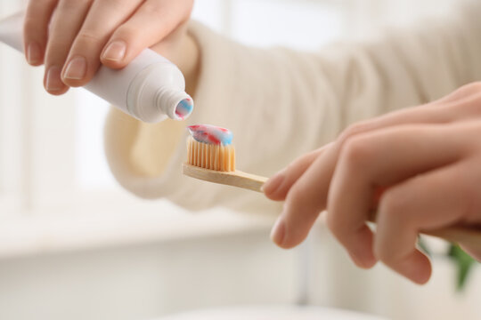 Person squeezing toothpaste onto a bamboo toothbrush, daily oral hygiene and Sustainable dental care routine, Sustainable dental care practices and eco friendly personal grooming habits
