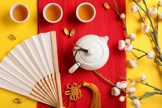 Traditional tea with paper fan and Chinese symbols on yellow background
