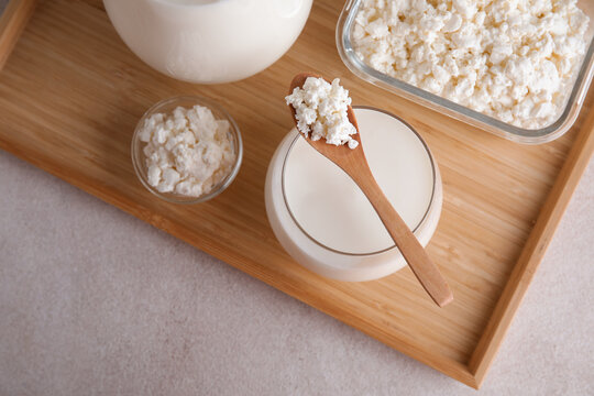 Glass of fresh kefir and bowls with cottage cheese on white background