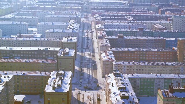 Aerial view of a snowy post soviet city with traffic moving along a central street in winter