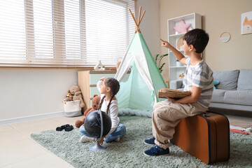Obraz premium Cute children with adventure book pointing at something in room