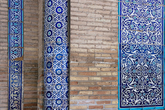 Ornate blue ceramic tilework and brick wall detail at Islam Khoja Madrasah in Khiva. Intricate geometric and floral patterns in traditional Uzbek architectural decoration. Ideal for travel.