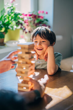 Smiling child playing wooden block game at home with family
